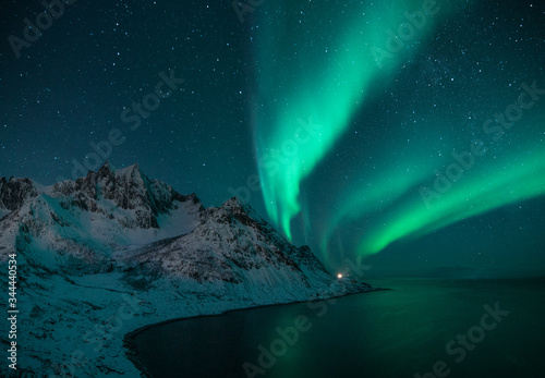 polar lights also called northern lights or aurora borealis in northern norway during winter above a fjord and snow covered mountains