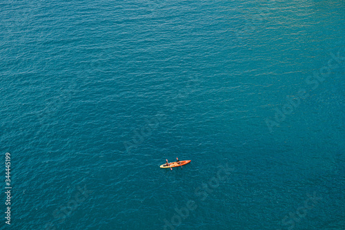 Two people row oars in one yellow-red kayak against the texture of the sea. Concept banner travel. Aerial top view.