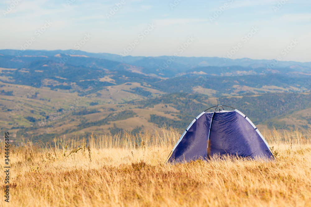 Morning landscape in the mountains with blue tent. Camping vacation concept