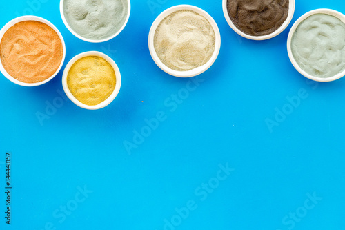 cosmetic clay - Yellow, red, white, blue and black dry powder - top-down flat lay on yellow table copy space