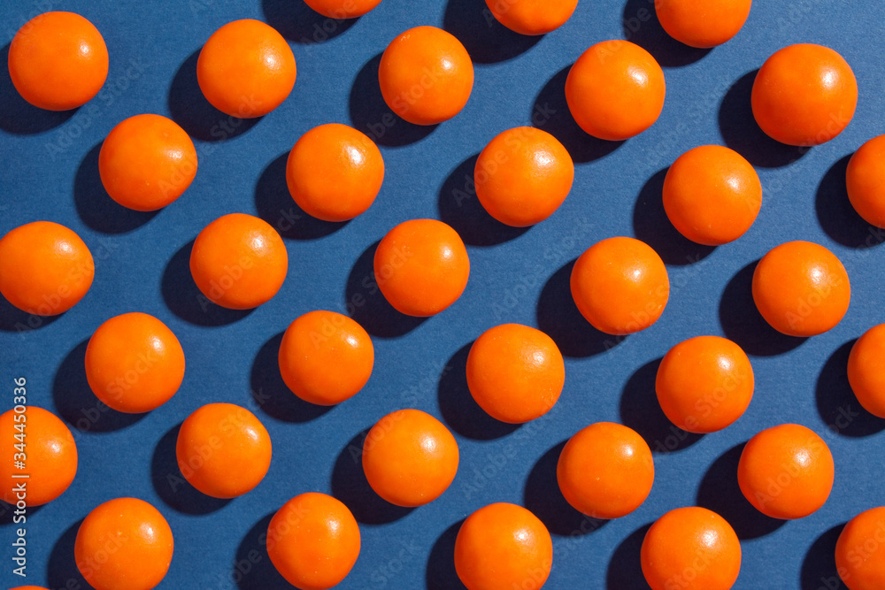 Orange round chocolate candies on a blue background with a tight shadow Orange round chocolate candies on a blue background with a tight shadow
