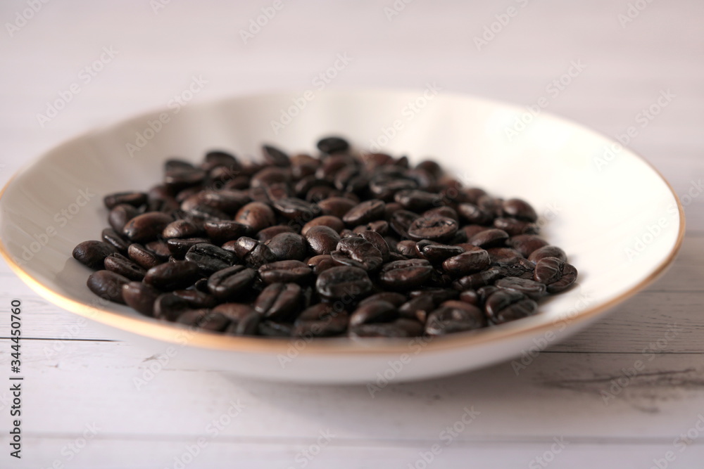 Coffee beans are in a white porcelain saucer Coffee beans are in a white porcelain saucer