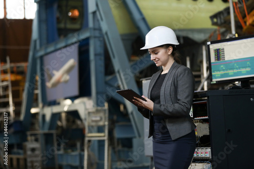 Wallpaper Mural Portrait of a female factory manager in a white hard hat and business suit. Controlling the work process at the airplane manufacturer. Torontodigital.ca