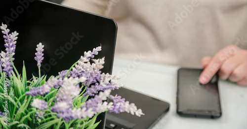 blurry businesswoman in pullover types on black smartphone and on notebook close view