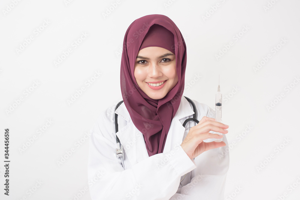 Beautiful woman doctor with hijab is holding syringe on white background Beautiful woman doctor with hijab is holding syringe on white background