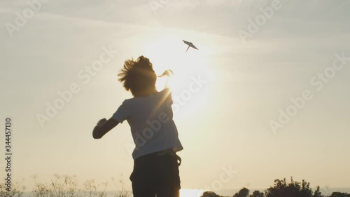 Back view of kid playing with paper plane in park