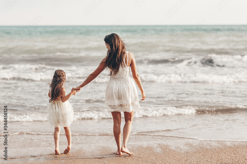 Happy mother and daughter enjoying sunny day on the beach