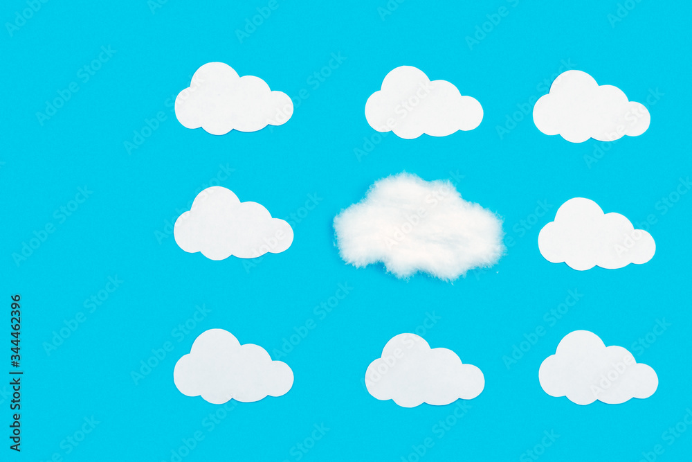 Blue background with white clouds out of paper. Stand out from the crowd, be different from everyone else