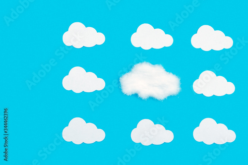 Blue background with white clouds out of paper. Stand out from the crowd, be different from everyone else