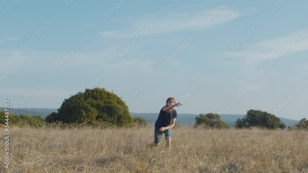 Schoolboy throwing paper plane in field on summer day Schoolboy throwing paper plane in field on summer day