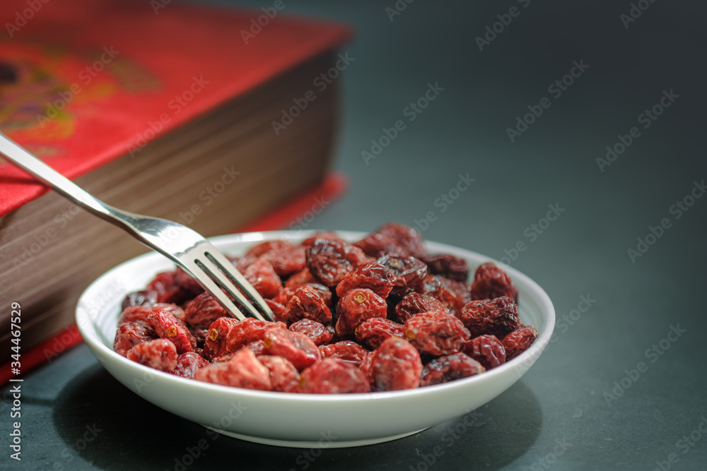 Closeup view of a White plate Full of Dried Cranberries and vintage book Closeup view of a White plate Full of Dried Cranberries and vintage book