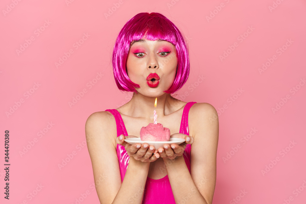 Image of young beautiful woman in wig blowing out candle on cake Image of young beautiful woman in wig blowing out candle on cake
