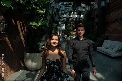 beautiful couple-a girl in a magnificent dress and a guy in a black shirt and trousers are in a building with a beautiful interior