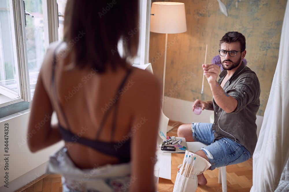 Fototapeta premium Man painting portrait of sexy woman. Creating artwork.