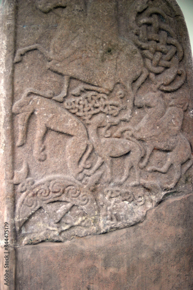 Ancient abstract design carved onto a standing stone in northern europe. Shows animals and riders on horses possibly hunting. Ancient abstract design carved onto a standing stone in northern europe. Shows animals and riders on horses possibly hunting.