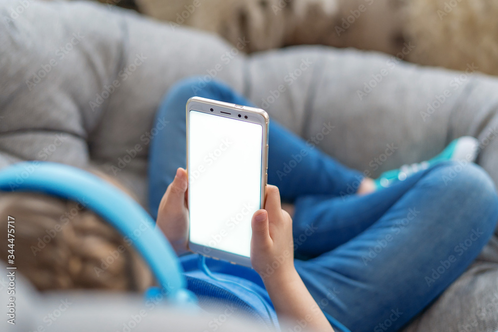 little girl with headphones and holding smartphone white screen in her hands little girl with headphones and holding smartphone white screen in her hands