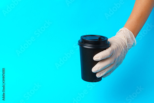 Coffee delivery. Human hand holding takeaway coffee cup on paper background