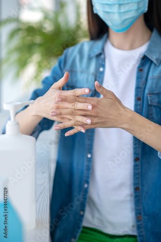 Young woman in a mask disinfecting her hands