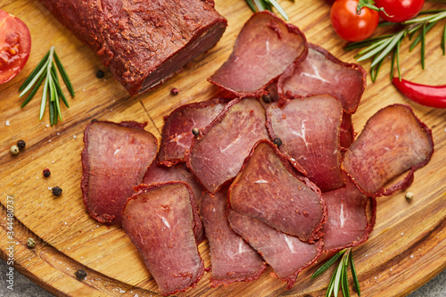 Armenian basturma or Pastirma on wooden cutting board decorated with spices, lettuce, lemon and tomatoes. Meat smoked jerky good as Beer snack