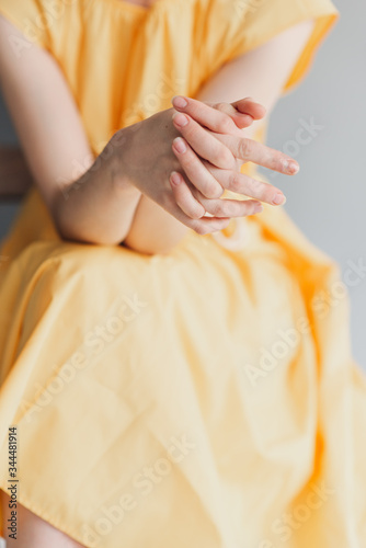 A young girl's thin hands. Girl in a yellow dress 