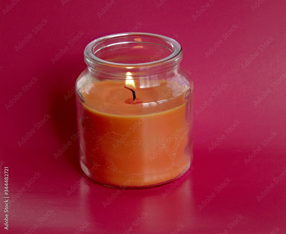 a fragrant pink candle in a decorative jar flickers with its fire. a fragrant pink candle in a decorative jar flickers with its fire.