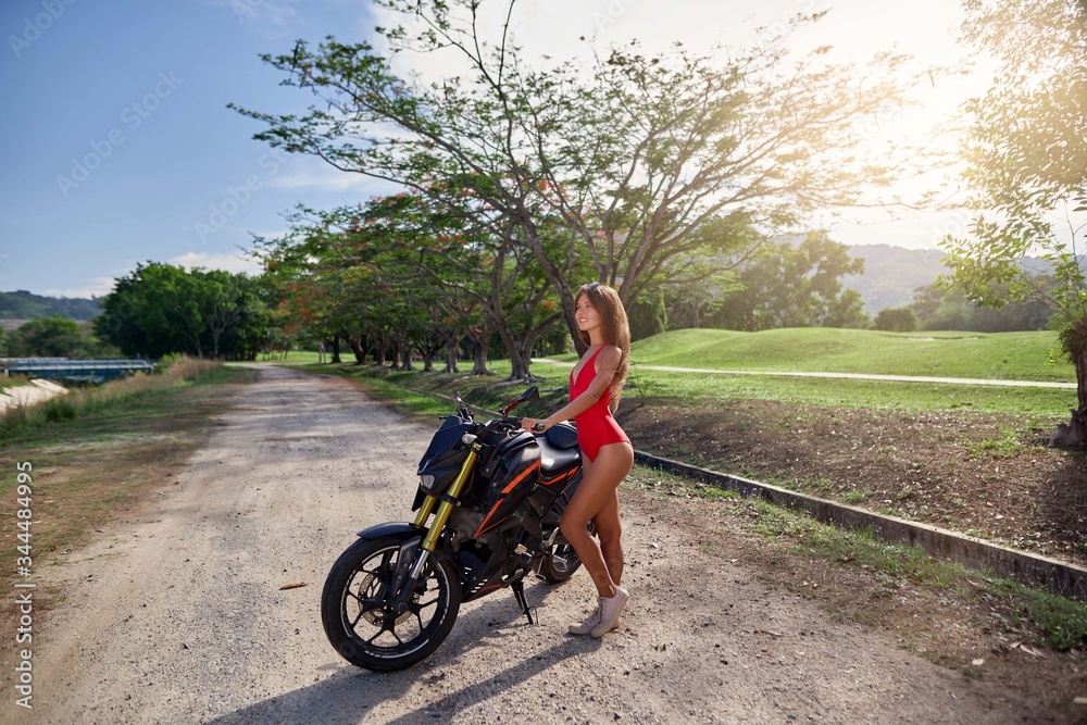 Fototapeta premium Outdoor fashion portrait of pretty young woman in bikini on a motorcycle 