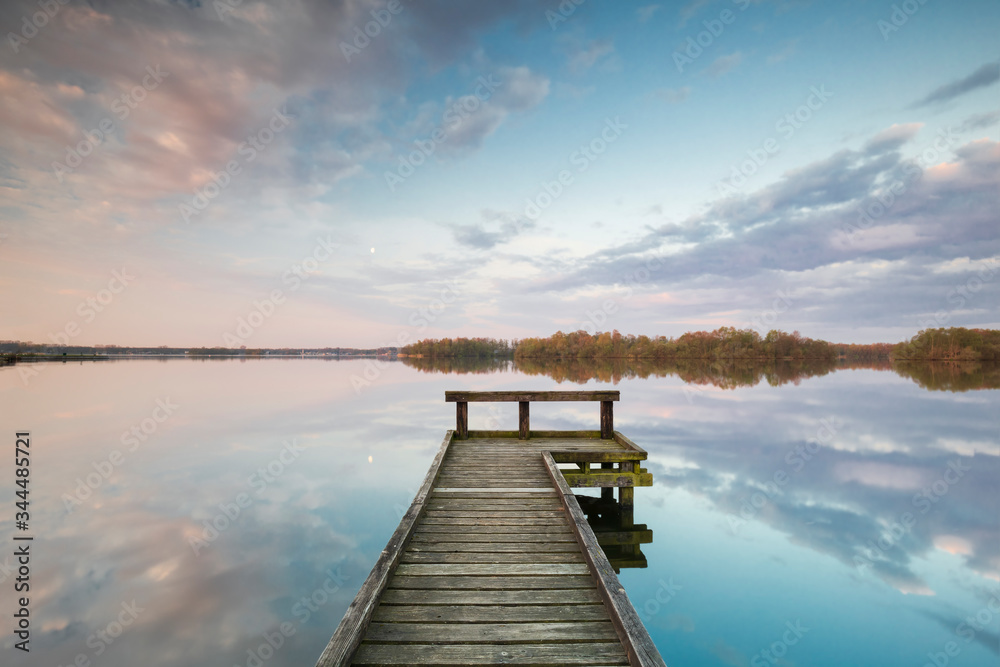 wooden pier on big lake with sky reflected