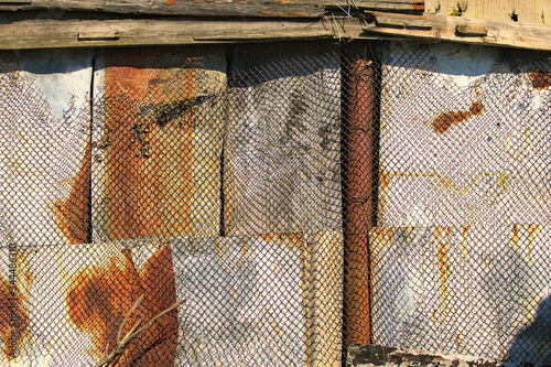 Vintage aged rusty metal wall with rabitz. Iron metal wall with rusted and aged metal grid. The wall of abandoned barn. Abstract background