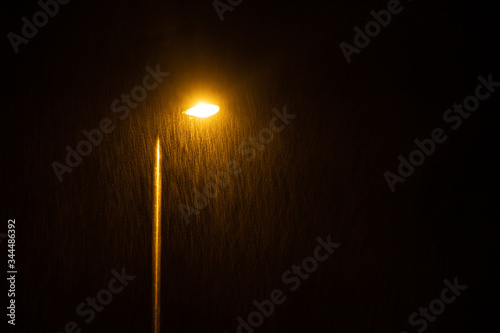A glowing street lamp at rainy night.