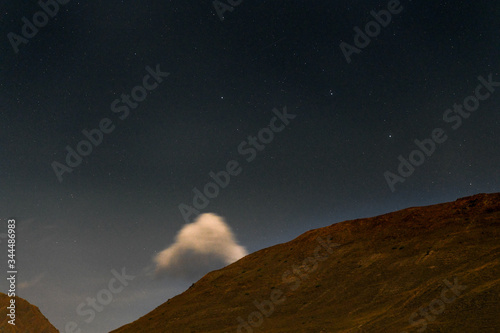 The Tusheti Mountains at night under a starry sky with a moving cloud