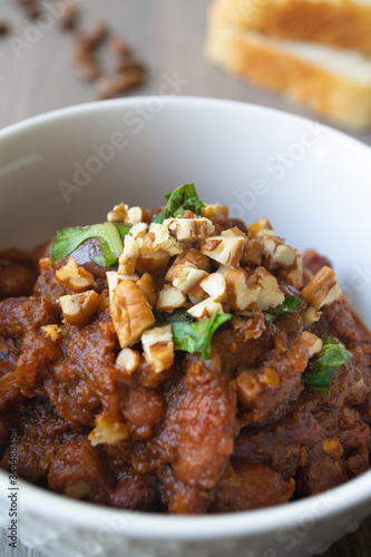 Traditional Georgian vegan kidney beam stew lobio with chopped walnuts and parsley served in a bowl with slices of bread