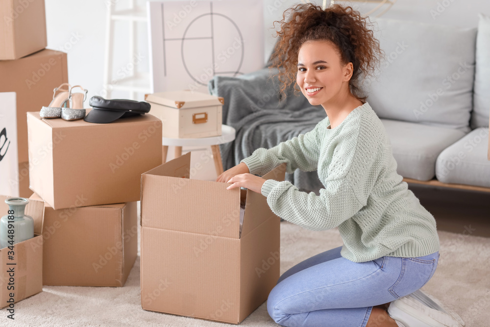 Young woman unpacking moving boxes in her new home Young woman unpacking moving boxes in her new home