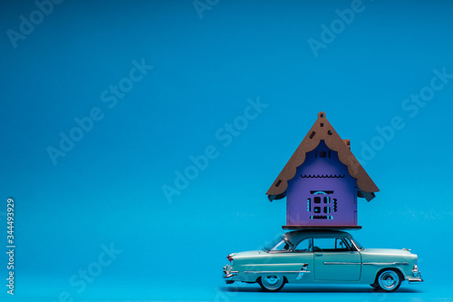 A purple house on top of a light blue car, on blue background.