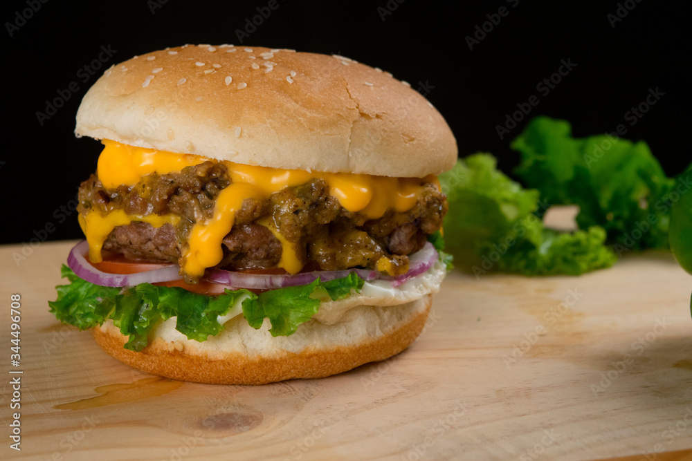 Tasty Hamburger With Lettuce Cheese on Wooden Table and Dark Background