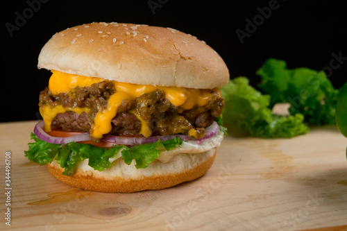 Tasty Hamburger With Lettuce Cheese on Wooden Table and Dark Background