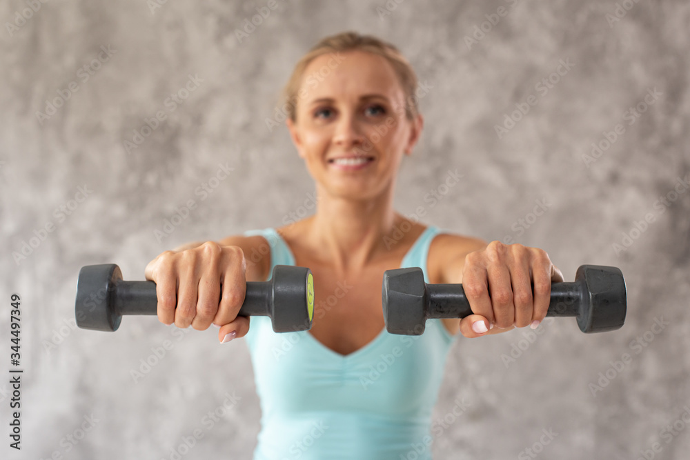 Smiling woman in sport outfit holds two dumbbells in hands. Portrait photo. Selective focus Smiling woman in sport outfit holds two dumbbells in hands. Portrait photo. Selective focus