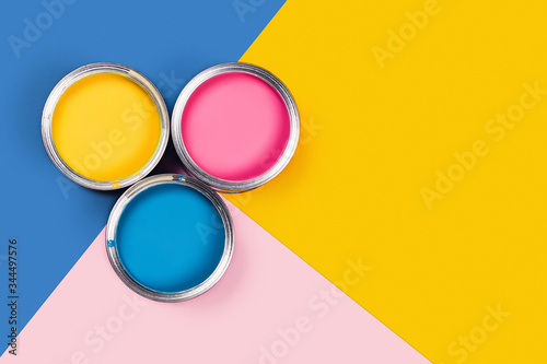 Repare concept. Tricolor blue, yellow, pink background with three colors paint cans. Flat lay, top view, copy space.