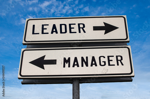 Leader vs manager. White two street signs with arrow on metal pole with word Leader and Manager. Directional road. Crossroads Road Sign, Two Arrow. Blue sky background.