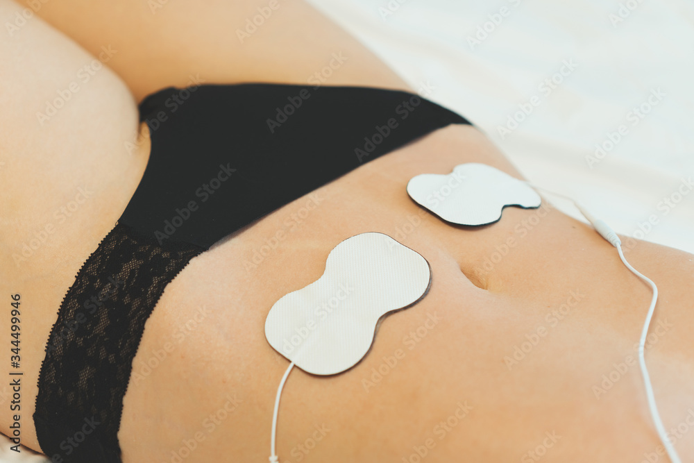 Woman body with electrodes on her stomach. Electrical muscle