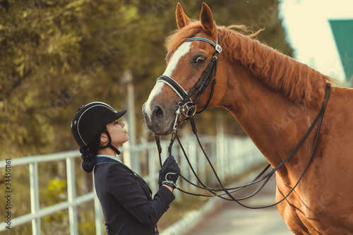 horsewoman jockey in uniform standing with black horse outdoors © matilda553