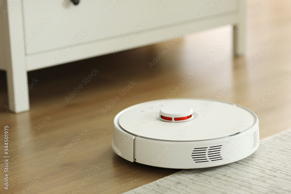 white robot vacuum cleaner cleans the floor from debris,home cleaning with an electric vacuum cleaner,vacuum cleaner electric robot cleaning technology,top view of a robot vacuum cleaner. white robot vacuum cleaner cleans the floor from debris,home cleaning with an electric vacuum cleaner,vacuum cleaner electric robot cleaning technology,top view of a robot vacuum cleaner.