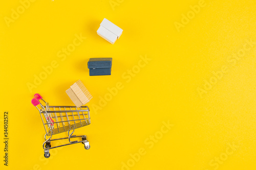 Shopping concept. Shopping carts and packages with gifts isolated on yellow background.