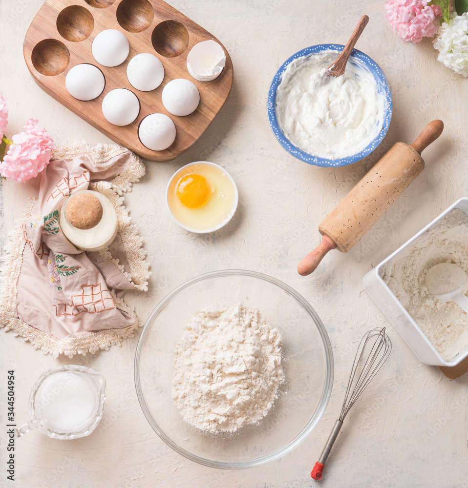 Modern baking background with flour in bowl, eggs and ingredients on white kitchen table background, top view. Home Bake. Recipes to cookies, pie and cake Modern baking background with flour in bowl, eggs and ingredients on white kitchen table background, top view. Home Bake. Recipes to cookies, pie and cake