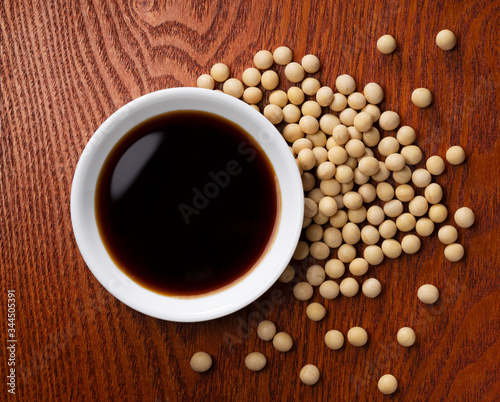 Soy sauce in a plate and soybeans scattered around