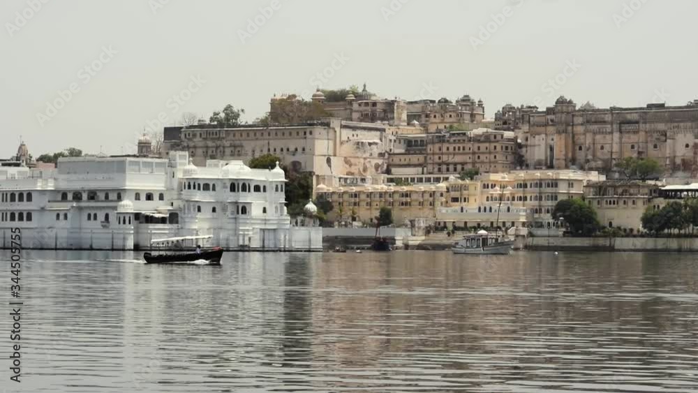 Lake Pichola and buildings in Udaipur, Rajasthan, India. Video made from a moving boat. On the shore are visible traditional Indian think a boat is sailing by. Lake Pichola and buildings in Udaipur, Rajasthan, India. Video made from a moving boat. On the shore are visible traditional Indian think a boat is sailing by.