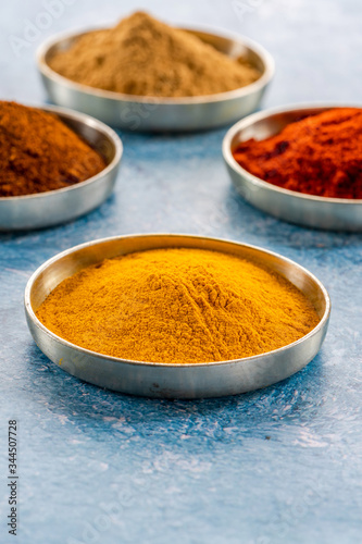 Ground spices in pots - tumeric, paprika, chilli and curry powder - closeup with selective focus