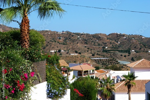View over village rooftops towards the mountains, Macharaviaya, Andalusia, Spain. photo