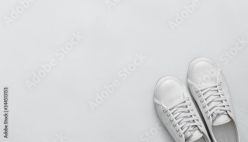 White leather sneakers on blue background. Pair of fashion trendy white sport shoes or sneakers with copy space for text or design. Overhead shot of new white sneakers. Top view or flat lay. Banner