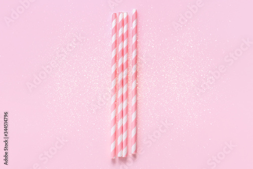 Obraz na plátně Pastel paper straws with white stripes on soft pink background with sparkles