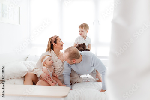 A young happy family with young children lying around  hugging  laughing on the bed at house